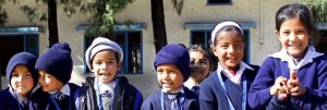 Young school children in India smiling and wearing hats to keep warm