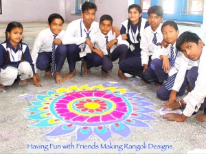 A group of Indian adolescent school children in blue and white uniforms around a colourful design made out of flour on the floor 