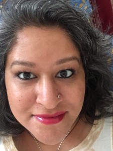 An Indian woman with a nose stud smiles at the camera